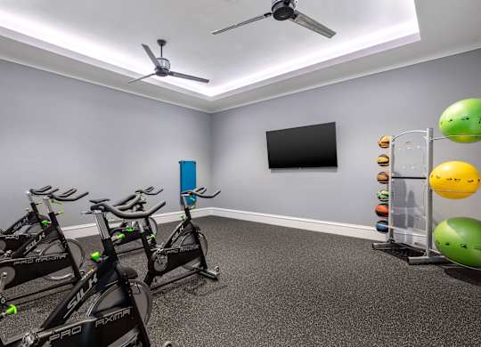 A room with exercise bikes and a fan.