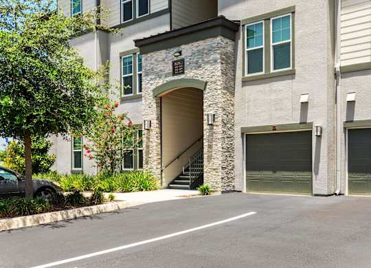 A modern two-story house with a stone archway entrance and two garage doors.