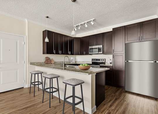 A kitchen with a white door and a counter with a bowl of fruit on it.
