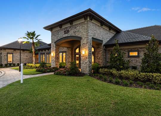 A house with a stone facade and a palm tree in front.