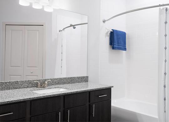 A bathroom with a sink, mirror, and shower.
