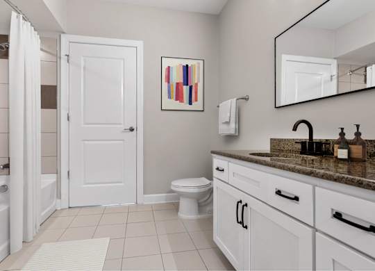 A bathroom with a white door, a toilet, a sink, and a mirror.