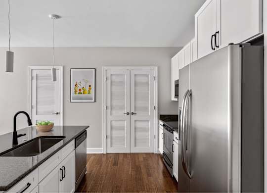 A modern kitchen with a stainless steel refrigerator and wooden floors.