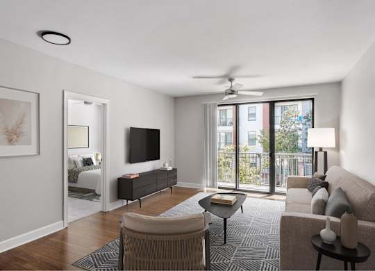A living room with a television, a couch, a chair, a table, and a fan.