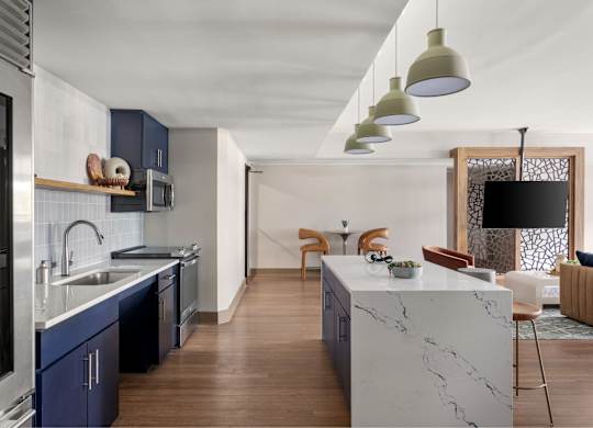 A modern kitchen with a marble island and wooden floors.