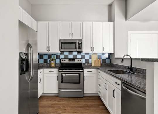 A modern kitchen with white cabinets and stainless steel appliances.