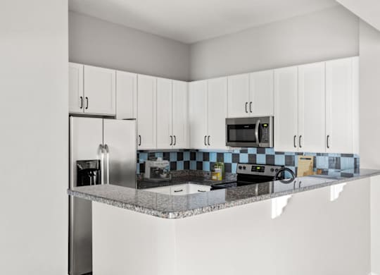A kitchen with white cabinets and a checkered backsplash.