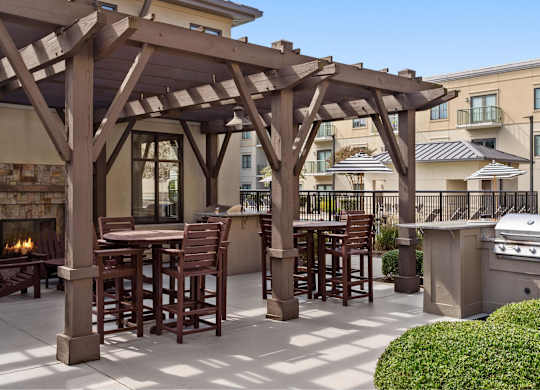 A patio with a fireplace and a pergola.
