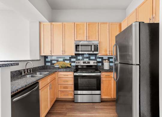A kitchen with wooden cabinets and a black refrigerator.