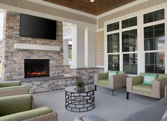 A living room with a stone fireplace and a flat screen TV mounted above it.