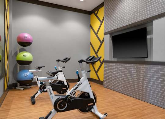 A Spinning bike is in the foreground of a brightly colored gym.