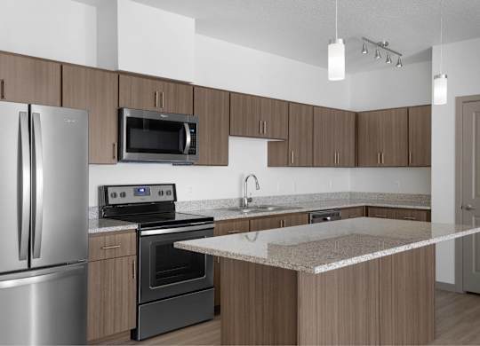 A kitchen with a refrigerator, oven, microwave, and sink.