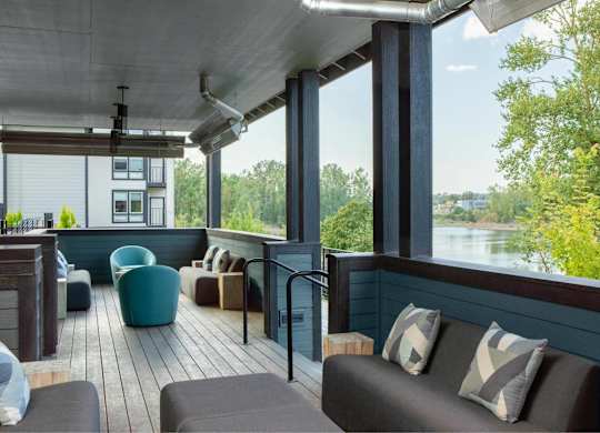 A patio with a couch and chairs overlooking a body of water.
