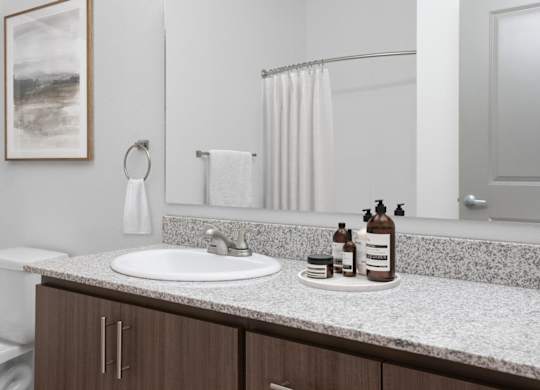A bathroom with a white sink and brown cabinets.