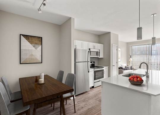 A modern kitchen with a wooden dining table and grey chairs.