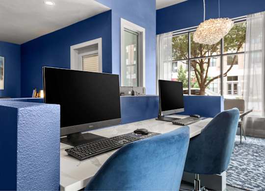 A blue chair is in front of a desk with a computer monitor and keyboard.