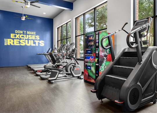 A gym with a row of treadmilers and elliptical machines.