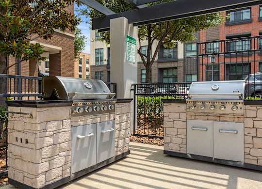 Two stone BBQs are in a sunny courtyard.