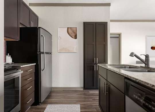 A kitchen with dark brown cabinets and a black refrigerator.