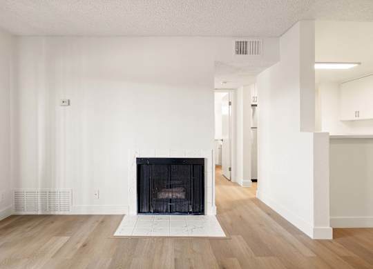 A large, empty room with a fireplace at the center.