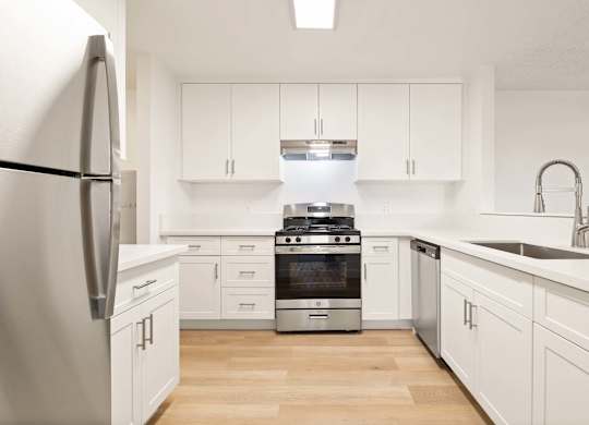 A modern kitchen with white cabinets and stainless steel appliances.
