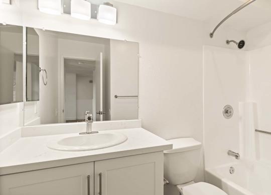 A white bathroom with a sink, toilet, and shower.