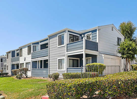 A grey and white building with a green lawn in front.