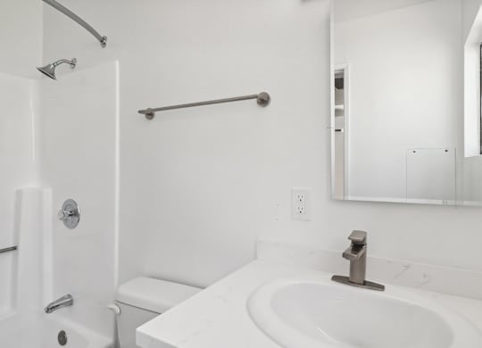 A white bathroom with a toilet, sink, and mirror.