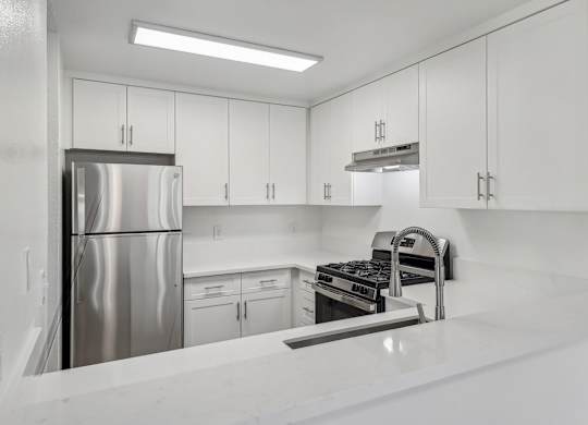 A modern kitchen with white cabinets and stainless steel appliances.