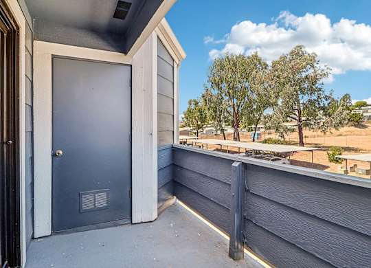 A blue door is on the left side of a grey house.
