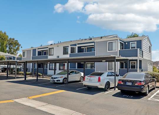 A parking lot with three cars parked in front of a building.