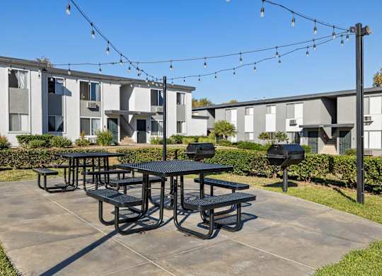 A black picnic table is in the middle of a concrete patio.