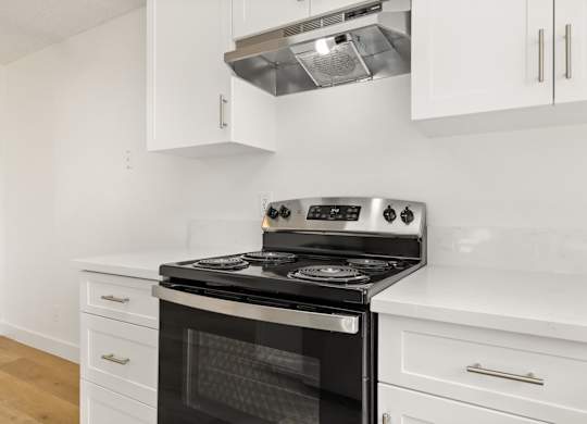 A modern kitchen with a stove top oven and white cabinets.