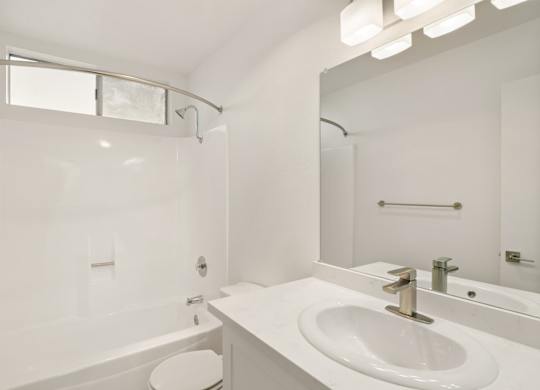 A white bathroom with a tub, toilet, and sink.