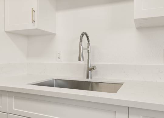 A modern kitchen with a white sink and faucet.