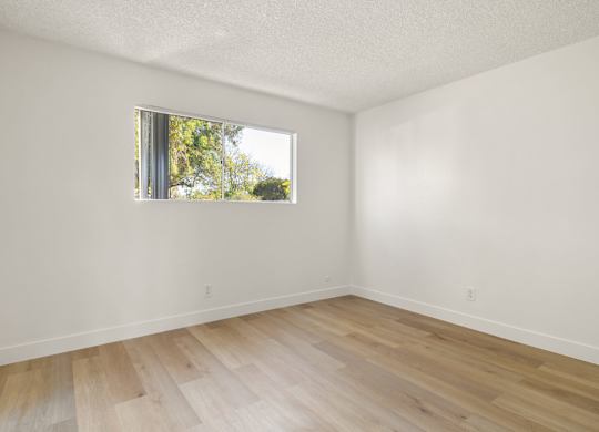 A room with a window and wooden flooring.