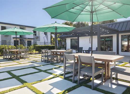 A patio with tables and chairs and umbrellas.
