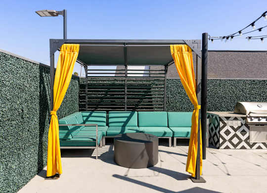 A patio area with a green couch and yellow curtains.