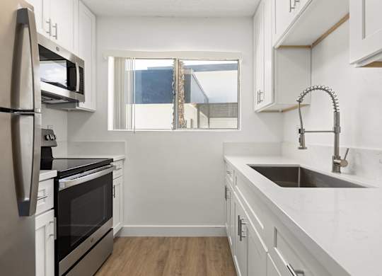 A modern kitchen with white cabinets and stainless steel appliances.