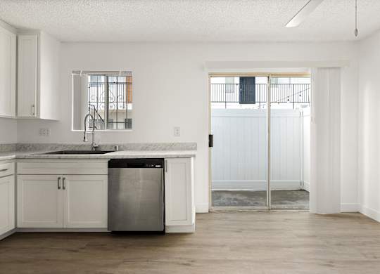 A kitchen with white cabinets and a marble countertop.