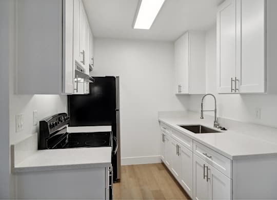 A kitchen with white cabinets and a black oven.