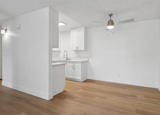 A kitchen with white cabinets and a wooden floor.