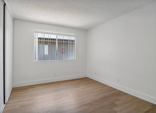 Empty room with a window and wooden floor.