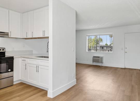 A kitchen with white cabinets and a window.
