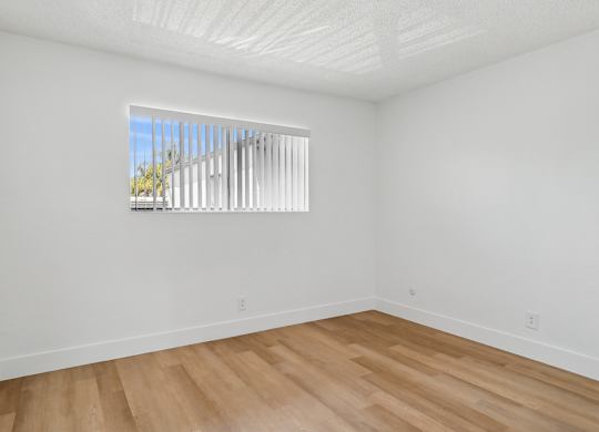 A room with a window and wooden flooring.