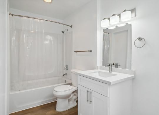 A white bathroom with a toilet, sink, and shower.