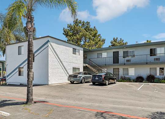 A parking lot with cars and a building in the background.