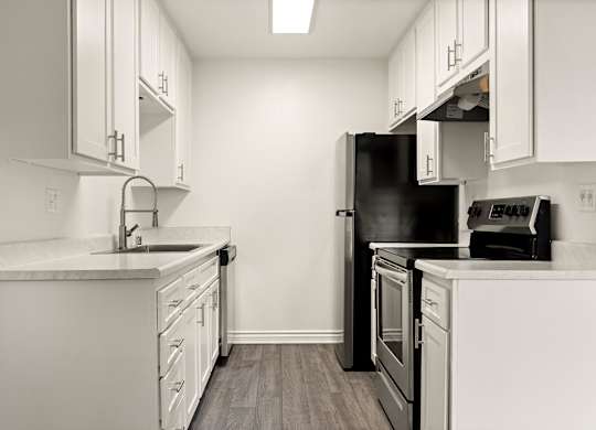 A kitchen with white cabinets and a black refrigerator.