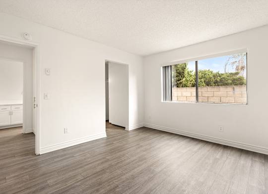A room with a large window and wooden flooring.