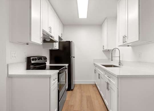A kitchen with white cabinets and a black refrigerator.